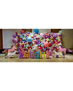 Pastel color balloon wallwith unicorn and name cutouts